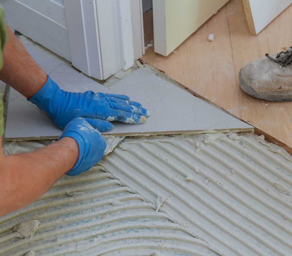 Plaster repair work laying tile, trowel in a man hand